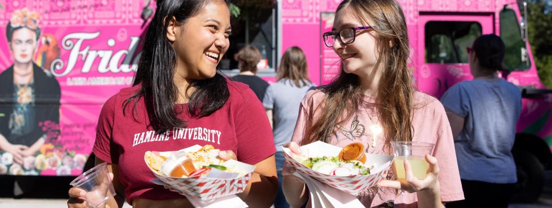 Two female students in front of food truck at Hamline Homecoming