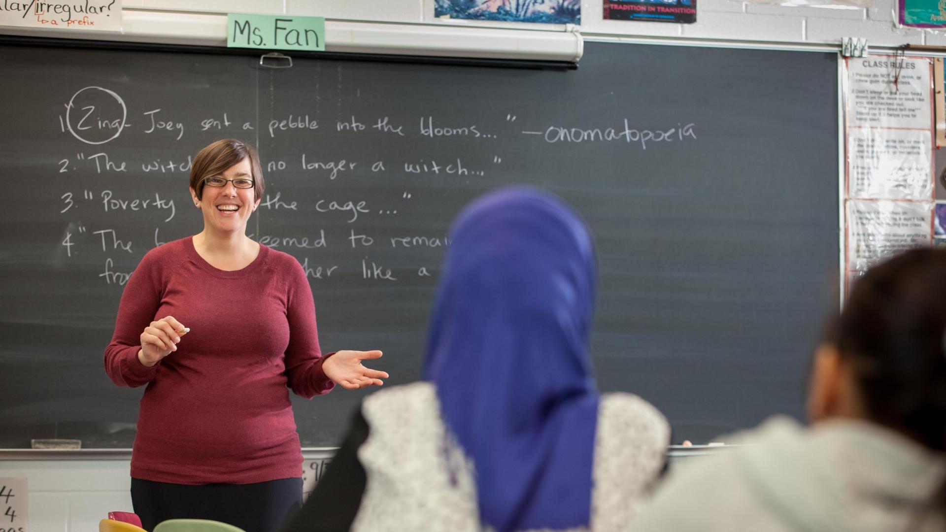 Teacher in front of blackboard, Hamline MA in Literacy Education