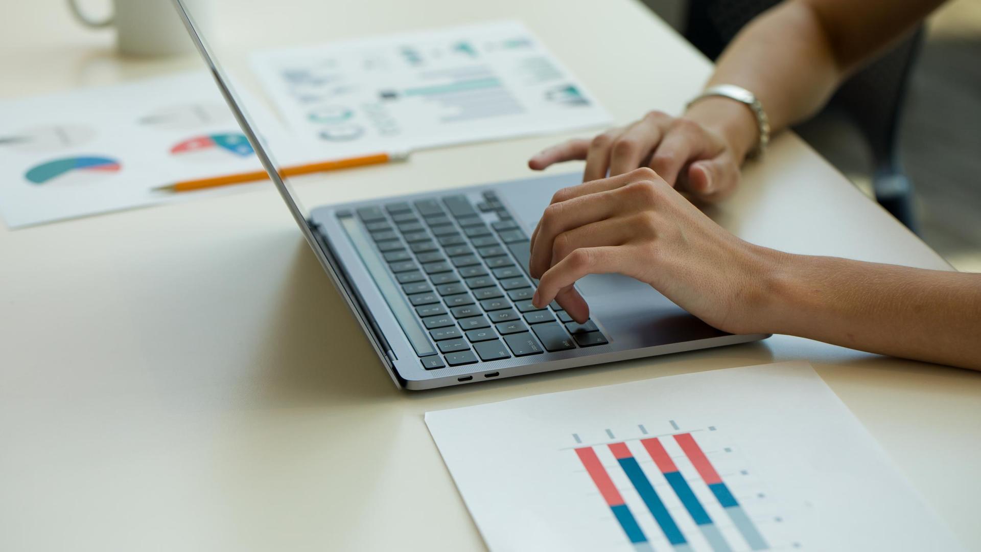 Typing on laptop with charts, business